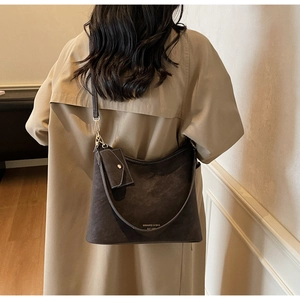 Detail of dark brown suede tote bag with adjustable strap and small envelope charm