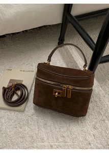 Détail d'un sac boîte en daim marron avec fermeture éclair dorée et finitions métalliques