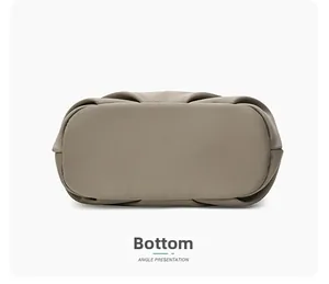 Detail view of the flat bottom and pleated edges of a khaki minimalist commuter bag