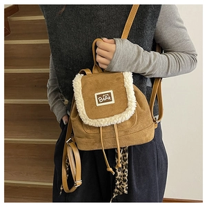 Brown suede backpack with white faux fur trim and bear logo tag on an indoor staircase