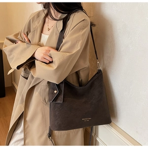 Detail of vintage brown tote bag with gold buckle and brand logo on autumn coat