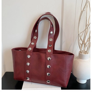 Detailed close-up of dark red vintage tote bag featuring silver rivet hardware accents