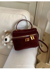 Détail du sac boîte en daim bordeaux avec ferrures dorées et breloque chiot mignonne