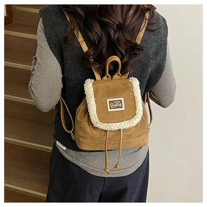 Detail of vintage brown corduroy backpack with white faux fur trim and bear patch logo