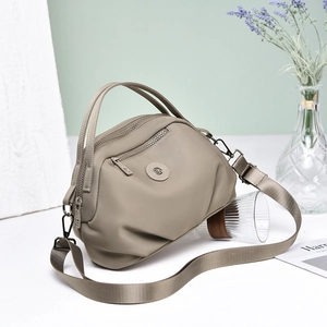 Detailed macro view of khaki nylon fabric texture and silver zipper pockets on the shoulder bag
