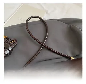 Detail of a dark brown PU leather handle with precise stitching and gold metal buckles