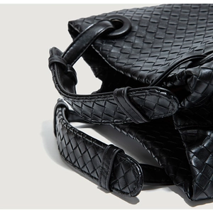 Macro detail of the premium black woven leather texture and metal ring on the bucket bag