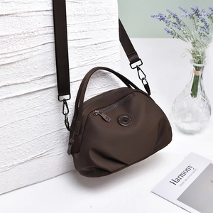 Detail of dark brown nylon hobo bag with adjustable wide strap and metal brand logo