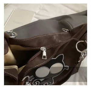 Gros plan du sac cabas marron avec broderie chat et fermeture éclair en métal argenté