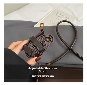 Detail of adjustable dark brown leather shoulder strap with golden metal hardware and hooks