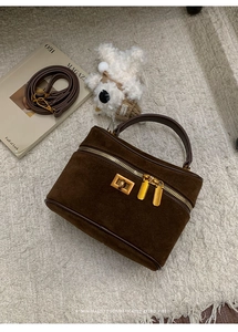 Vue de dessus du sac boîte en daim marron foncé avec détails dorés sur tapis
