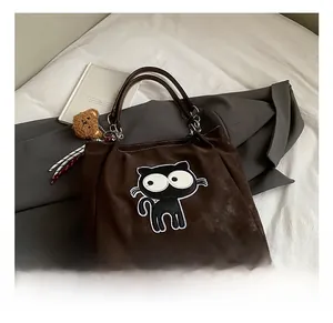 Détail du sac cabas marron foncé avec broderie chat noir et breloque ours en peluche