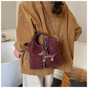Detail of vintage burgundy bucket bag featuring a cute dachshund leather charm and strap