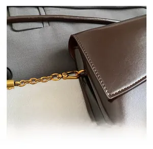 Detailed macro view of vintage gold metal hooks and chain strap on brown leather bag