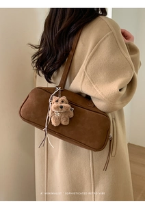 Detalle de bolso bandolera de ante marrón retro con amuleto de oso y placa de metal