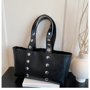 Detail view of black faux leather tote with silver stud accents and zipper closure