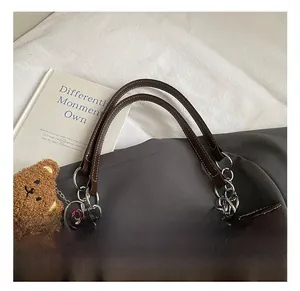 Détail du sac cabas marron foncé montrant les poignées en cuir et les chaînes argentées