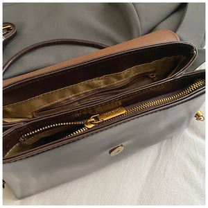 Detail shot of the spacious multi-pocket interior with gold zippers in a brown leather bag
