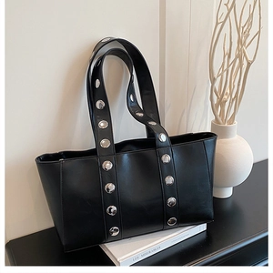 Detailed view of a black leather tote bag featuring silver stud accents and top handles