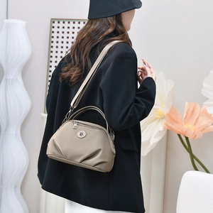 Khaki crossbody dumpling bag shown on model for size perspective in modern interior