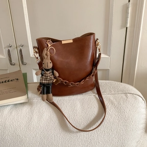 Detail of vintage brown bucket bag featuring a cute plush bunny charm on a white sofa