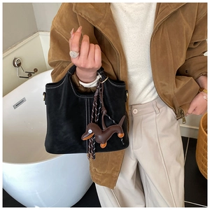 Detail of black matte handbag with white contrast stitching and a cute dachshund pendant