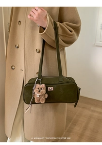Detalle del bolso de hombro verde oscuro de ante con hebilla plateada y llavero de oso