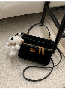 Détail du sac boîte en daim noir avec ferrures dorées et pendentif d'ours en peluche