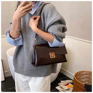Detail of dark brown leather shoulder bag with vintage gold buckle worn under the arm