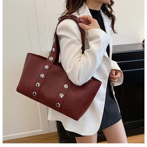 Close-up of wine red leather tote bag featuring large silver stud accents and texture