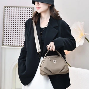 Model wearing a khaki nylon hobo bag with adjustable wide strap and gunmetal hardware