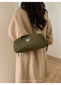Detalle del bolso de hombro de ante verde oscuro con cierre giratorio plateado estilo retro