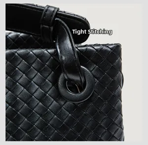 Macro shot of tight stitching and high-quality woven leather texture on a black handbag