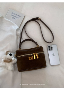 Vue détaillée du sac boîte en daim marron avec ferrures dorées et poignée en cuir