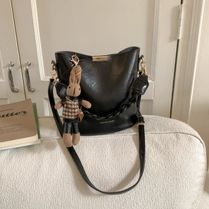 Detail of a vintage black bucket bag with thick chain strap and rabbit charm on sofa