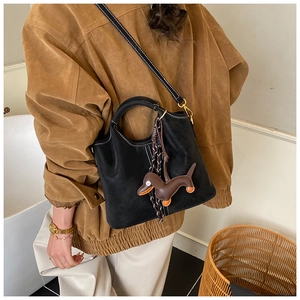 Detail of black matte leather bucket bag featuring white topstitching and dog charm