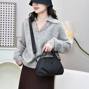 Minimalist black nylon crossbody bag with logo badge and wide strap on female model