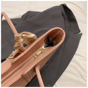 Detail der rosa Leder-Tote mit goldenem Reißverschluss und bedrucktem Seidenschal-Griff