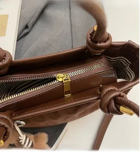 Detailaufnahme von glattem Goldreißverschluss und Streifenfutter an der Handtasche
