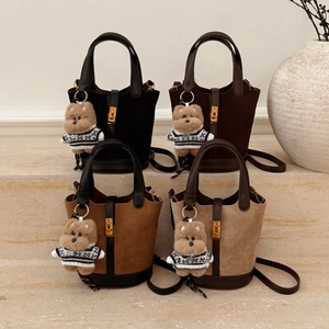Détail de quatre sacs seaux en daim avec garniture en cuir et breloques ours sur pierre