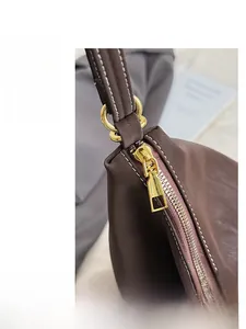 Gros plan sur la fermeture éclair dorée et coutures fines du sac fourre-tout en cuir