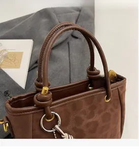 Nahaufnahme der braunen Wildledertasche mit feinen Nähten und Metallring-Details