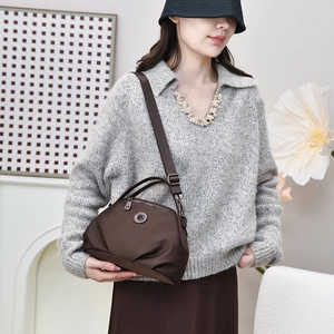 Close-up of dark brown nylon crossbody bag featuring a round logo and metal zipper detail