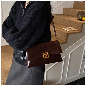 Detail of vintage brown shoulder bag showing suede texture and golden metal buckle