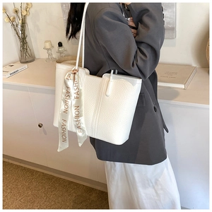 Nahaufnahme der weißen Tote-Bag aus Leder mit Lychee-Muster und modischem Seidenband