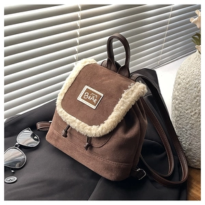 Close-up of brown suede backpack featuring white faux shearling trim and bear label detail
