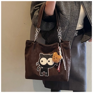 Détail d'un cabas en daim marron avec écusson chat noir et poignée en chaîne argentée