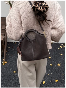 Detail of dark brown matte bucket bag featuring white stitching and top handle detail