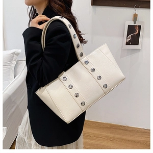 Détail du sac cabas crème avec bandoulière à gros rivets argentés et texture en similicuir
