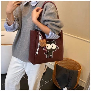 Détail du sac cabas en toile bordeaux avec broderie de chat et breloque ours en peluche